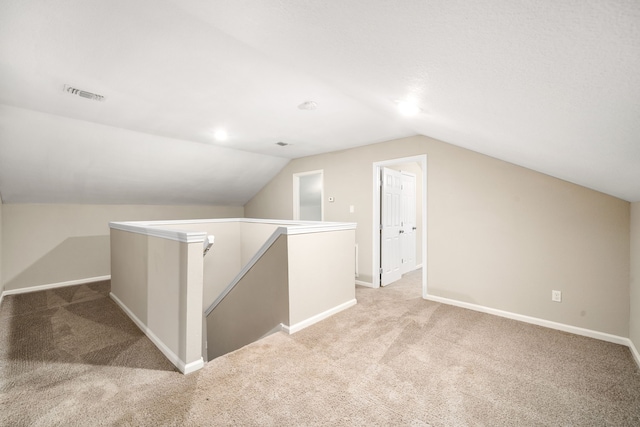 bonus room with light colored carpet and lofted ceiling