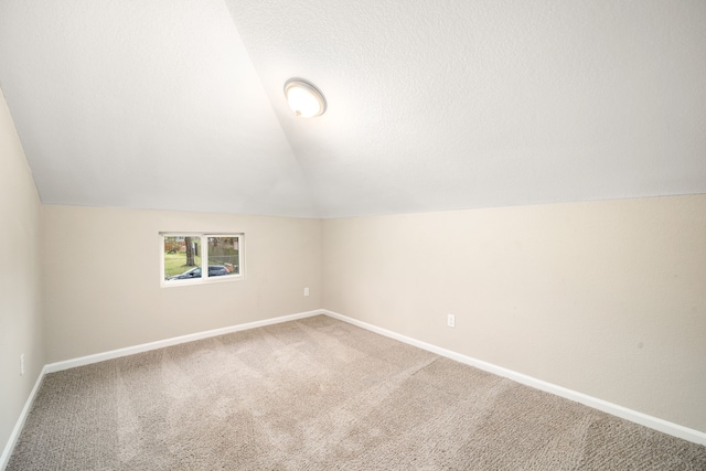 additional living space featuring lofted ceiling, carpet floors, and a textured ceiling