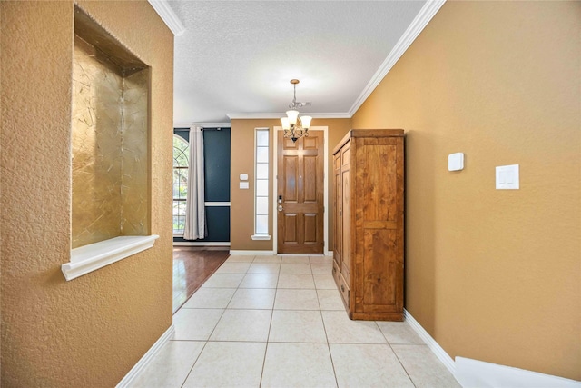 tiled entrance foyer featuring a textured ceiling, crown molding, and a notable chandelier