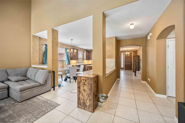 corridor featuring light tile patterned floors, a textured ceiling, and an inviting chandelier