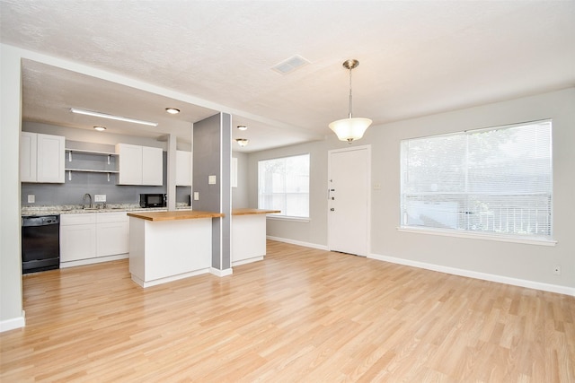 kitchen featuring light wood-type flooring, black appliances, pendant lighting, white cabinetry, and butcher block counters