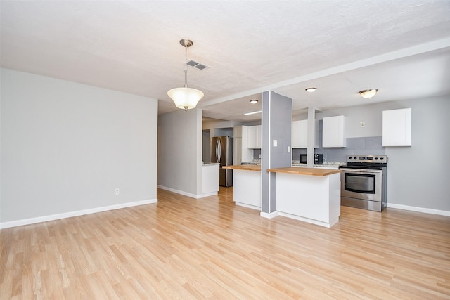 kitchen with appliances with stainless steel finishes, butcher block countertops, decorative light fixtures, a kitchen island, and white cabinetry