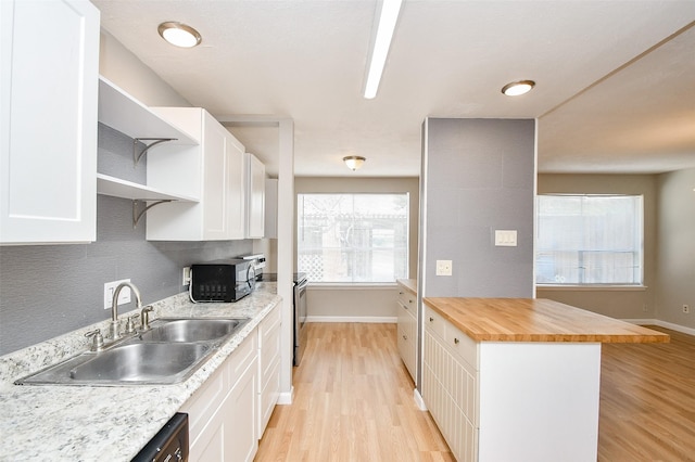 kitchen featuring light hardwood / wood-style floors, sink, electric range, white cabinets, and butcher block countertops