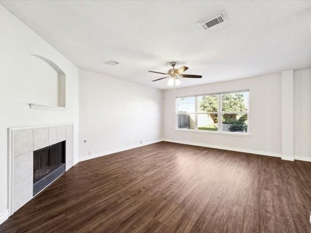 unfurnished living room with ceiling fan, a fireplace, and dark wood-type flooring