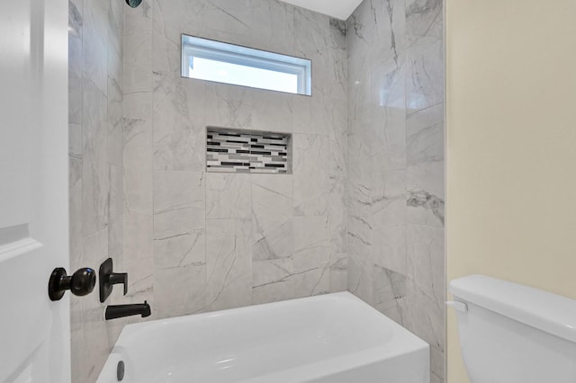 bathroom featuring toilet and tiled shower / bath