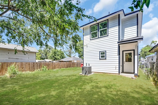 back of property with a yard and central AC unit