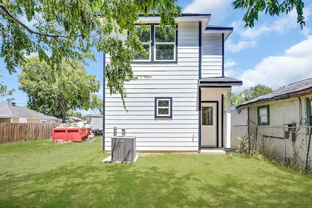 back of house with central air condition unit and a yard