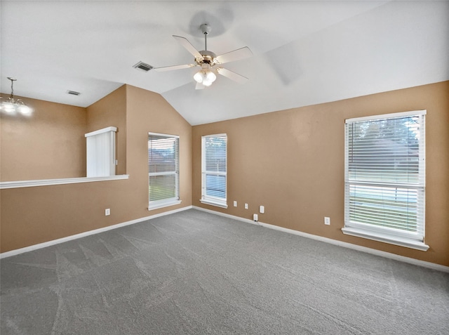 empty room with dark colored carpet, ceiling fan with notable chandelier, and vaulted ceiling