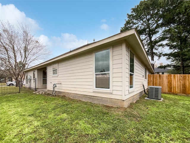 view of side of property featuring a lawn and central AC