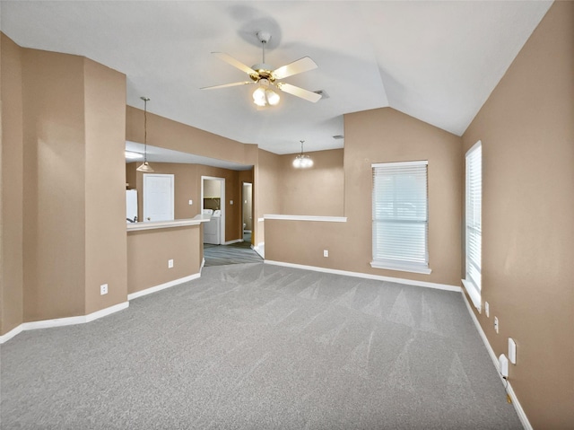 unfurnished living room with independent washer and dryer, ceiling fan with notable chandelier, carpet floors, and lofted ceiling