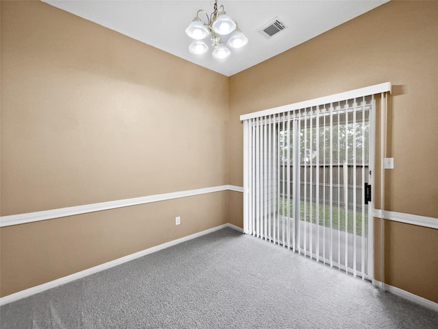 empty room with carpet floors and a notable chandelier