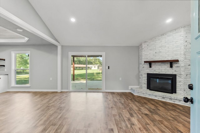 unfurnished living room with hardwood / wood-style floors, vaulted ceiling, and a brick fireplace