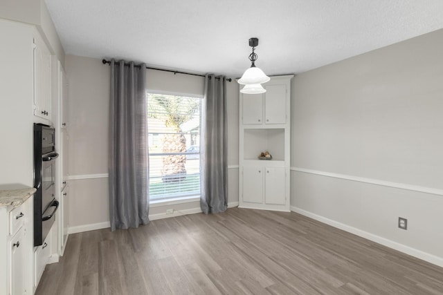 unfurnished dining area featuring light hardwood / wood-style floors and a textured ceiling