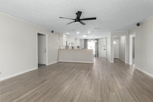 unfurnished living room with ceiling fan, light hardwood / wood-style floors, and a textured ceiling