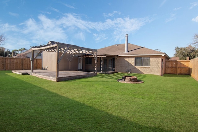 rear view of property featuring a pergola, a deck, an outdoor fire pit, and a lawn