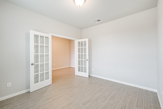 unfurnished room with french doors and light hardwood / wood-style flooring