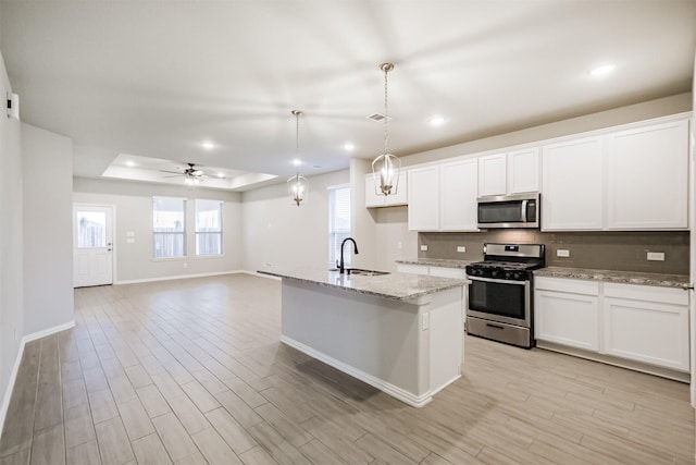 kitchen featuring ceiling fan, hanging light fixtures, stainless steel appliances, a tray ceiling, and white cabinets