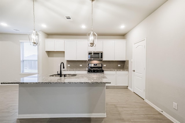 kitchen featuring pendant lighting, stainless steel appliances, a kitchen island with sink, and sink