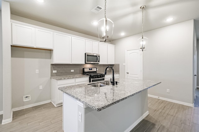 kitchen featuring hanging light fixtures, white cabinetry, a center island with sink, and stainless steel appliances