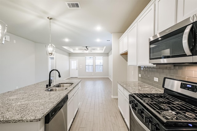 kitchen with stainless steel appliances, ceiling fan, sink, decorative light fixtures, and white cabinetry