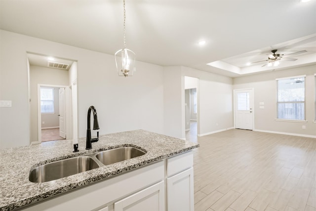 kitchen with pendant lighting, light stone counters, white cabinetry, and sink