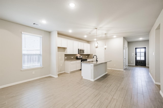 kitchen with stainless steel appliances, sink, pendant lighting, a center island with sink, and white cabinets