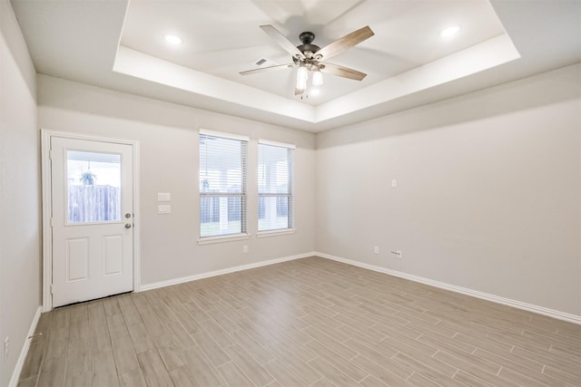 foyer featuring a raised ceiling, ceiling fan, and light hardwood / wood-style flooring