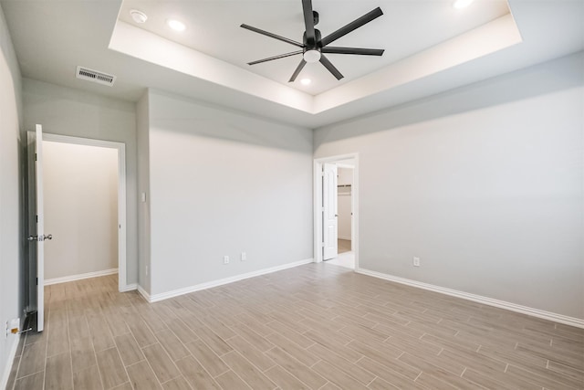 empty room featuring a raised ceiling and ceiling fan