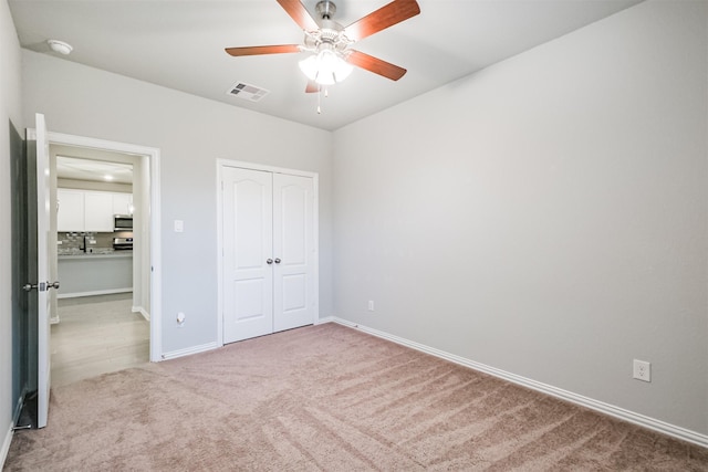 unfurnished bedroom featuring ceiling fan, light carpet, and a closet