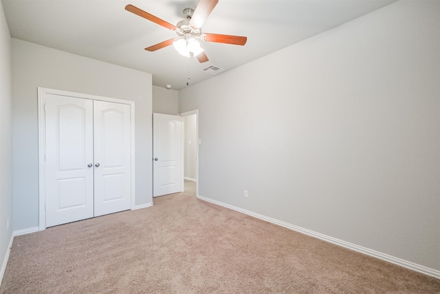 unfurnished bedroom featuring ceiling fan, a closet, and light colored carpet