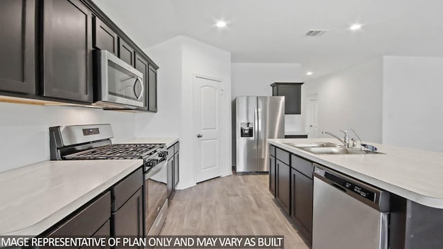 kitchen featuring a center island with sink, sink, light wood-type flooring, and stainless steel appliances