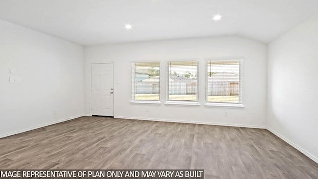 unfurnished room featuring lofted ceiling and light wood-type flooring