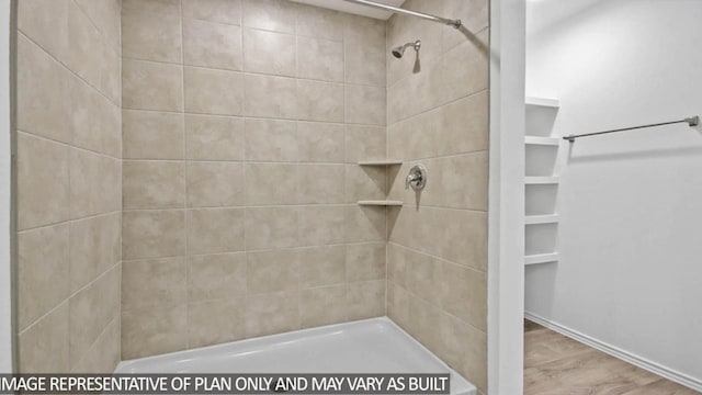 bathroom with a tile shower and wood-type flooring