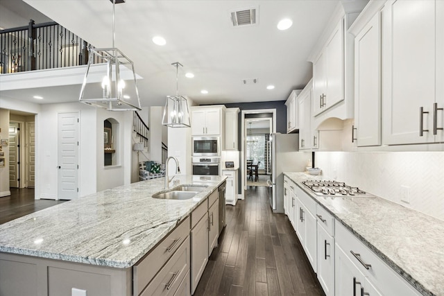 kitchen with sink, white cabinets, a large island, and decorative light fixtures