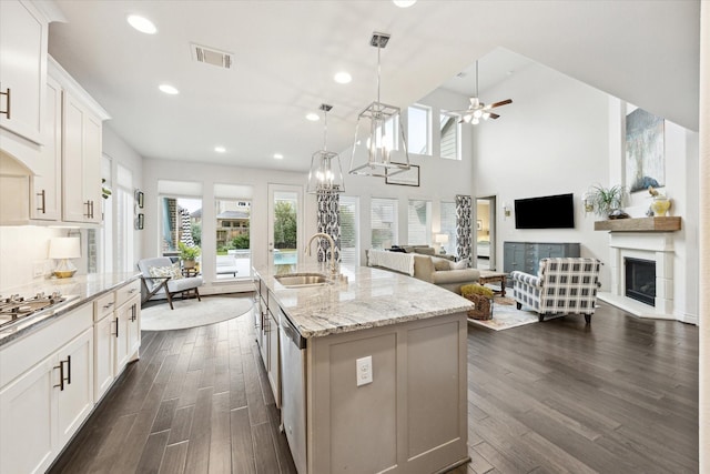 kitchen featuring sink, a center island with sink, decorative light fixtures, and white cabinetry