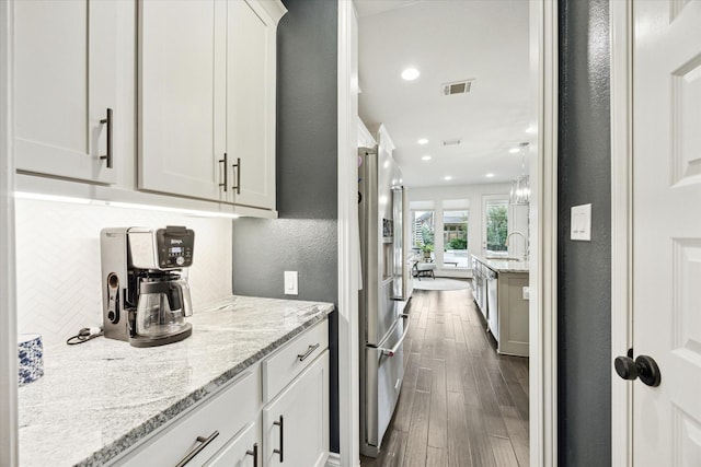 kitchen with white cabinets, backsplash, light stone countertops, dark hardwood / wood-style flooring, and appliances with stainless steel finishes