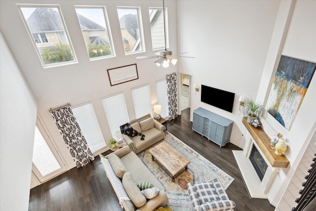 living room with a towering ceiling, ceiling fan, and dark hardwood / wood-style flooring