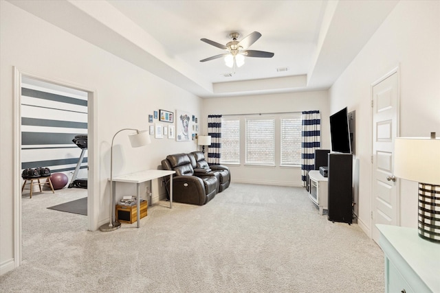 interior space with ceiling fan, light carpet, and a raised ceiling