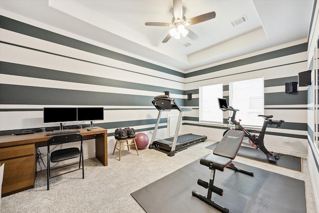 workout room with ceiling fan, light carpet, and a raised ceiling