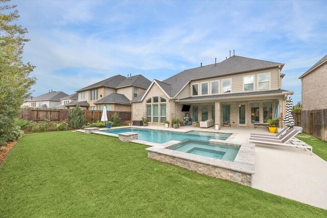 back of property featuring a lawn, a swimming pool with hot tub, and a patio