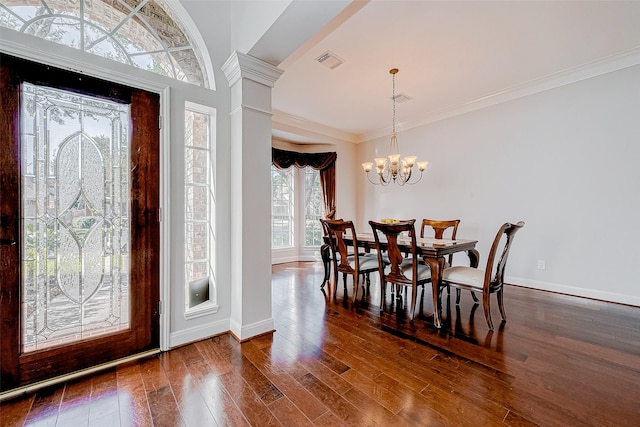 foyer with dark hardwood / wood-style flooring, an inviting chandelier, crown molding, and decorative columns