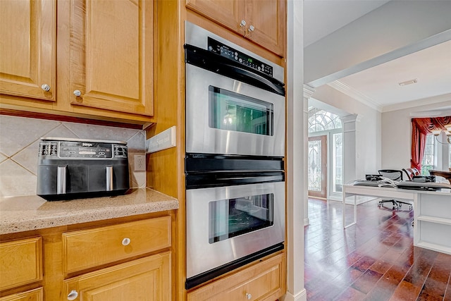 kitchen with dark wood-type flooring, light stone countertops, decorative backsplash, crown molding, and stainless steel double oven