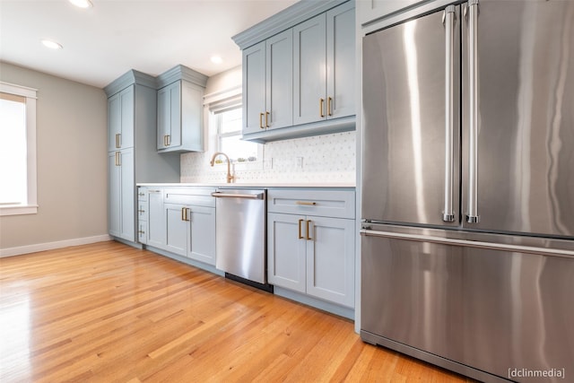 kitchen featuring light hardwood / wood-style flooring, decorative backsplash, plenty of natural light, and stainless steel appliances