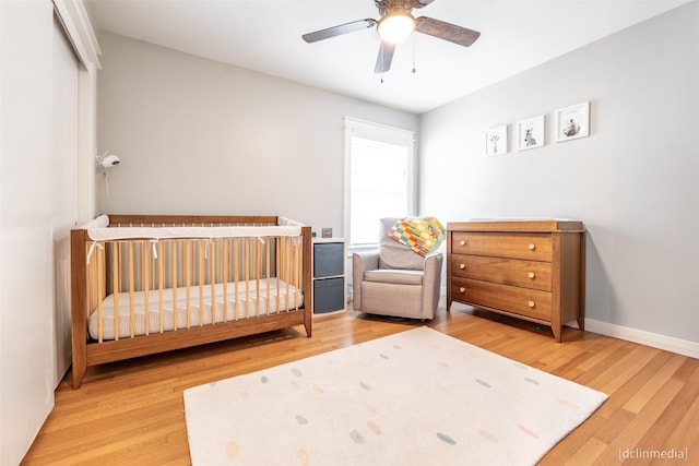 bedroom with a closet, light hardwood / wood-style flooring, a nursery area, and ceiling fan