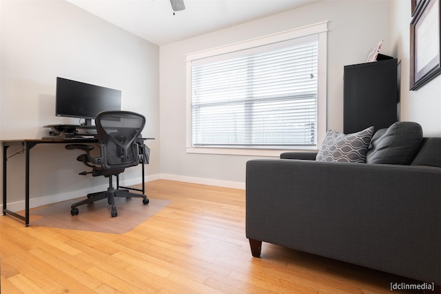 home office with light hardwood / wood-style floors and ceiling fan