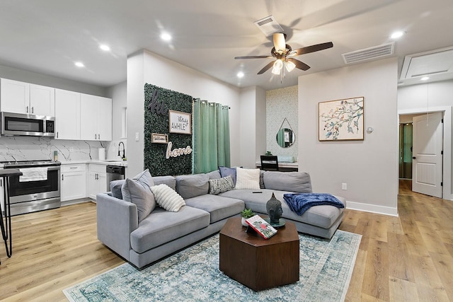 living room with ceiling fan, light hardwood / wood-style floors, and sink