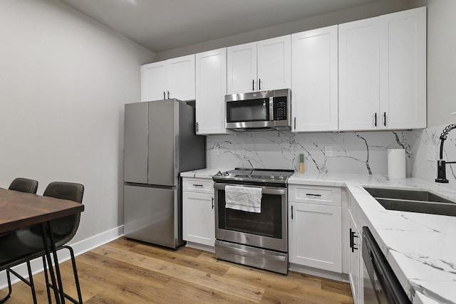 kitchen featuring sink, appliances with stainless steel finishes, tasteful backsplash, light hardwood / wood-style floors, and white cabinetry