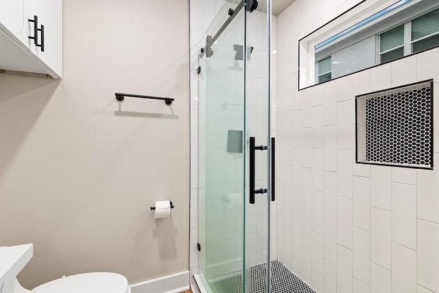 bathroom featuring toilet and a shower with shower door