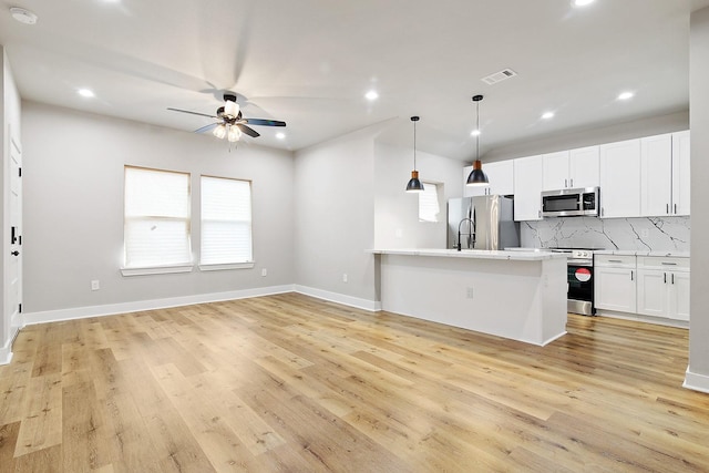 kitchen with white cabinetry, hanging light fixtures, light hardwood / wood-style floors, decorative backsplash, and appliances with stainless steel finishes