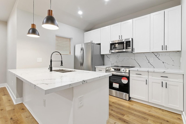 kitchen with light stone counters, hanging light fixtures, stainless steel appliances, and sink